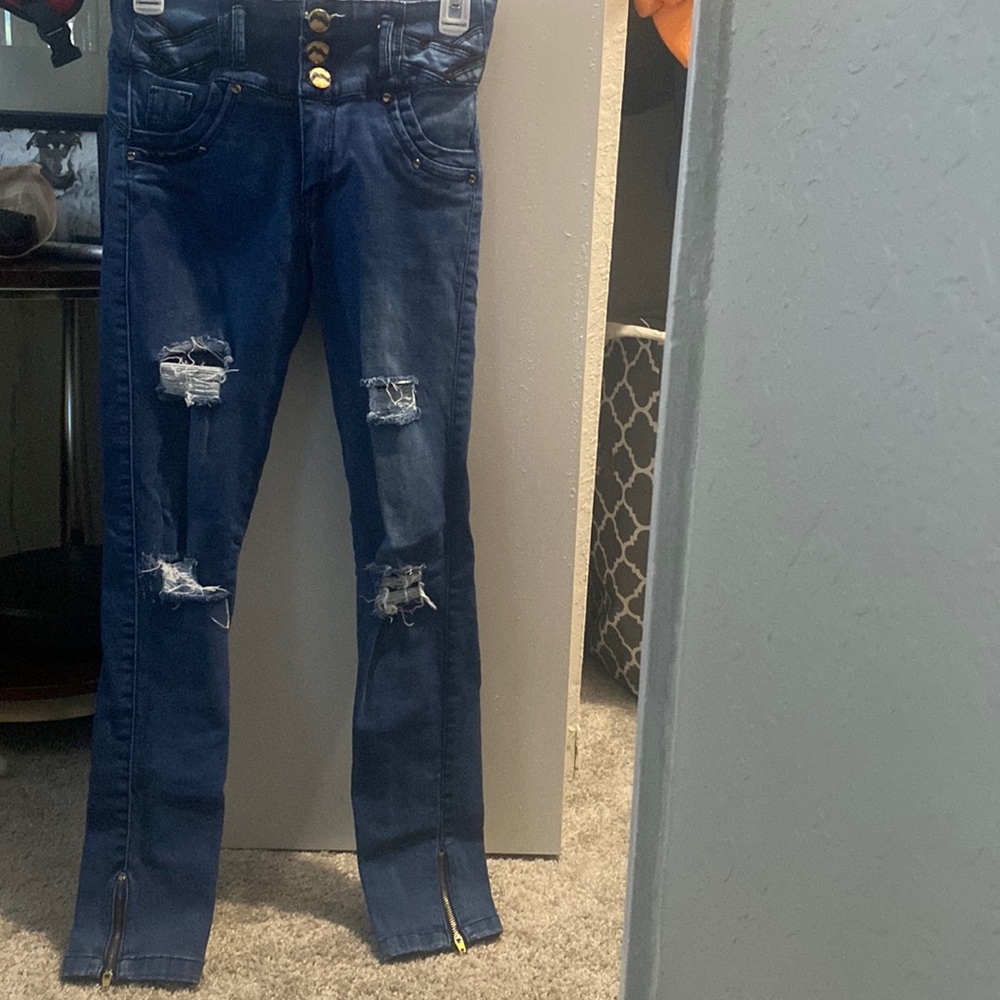 Selling dark ripped jeans with zippers at the bottom